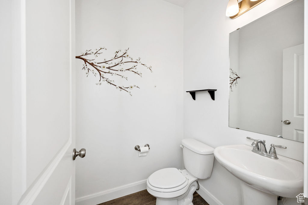 Bathroom with baseboards, toilet, wood finished floors, and a sink