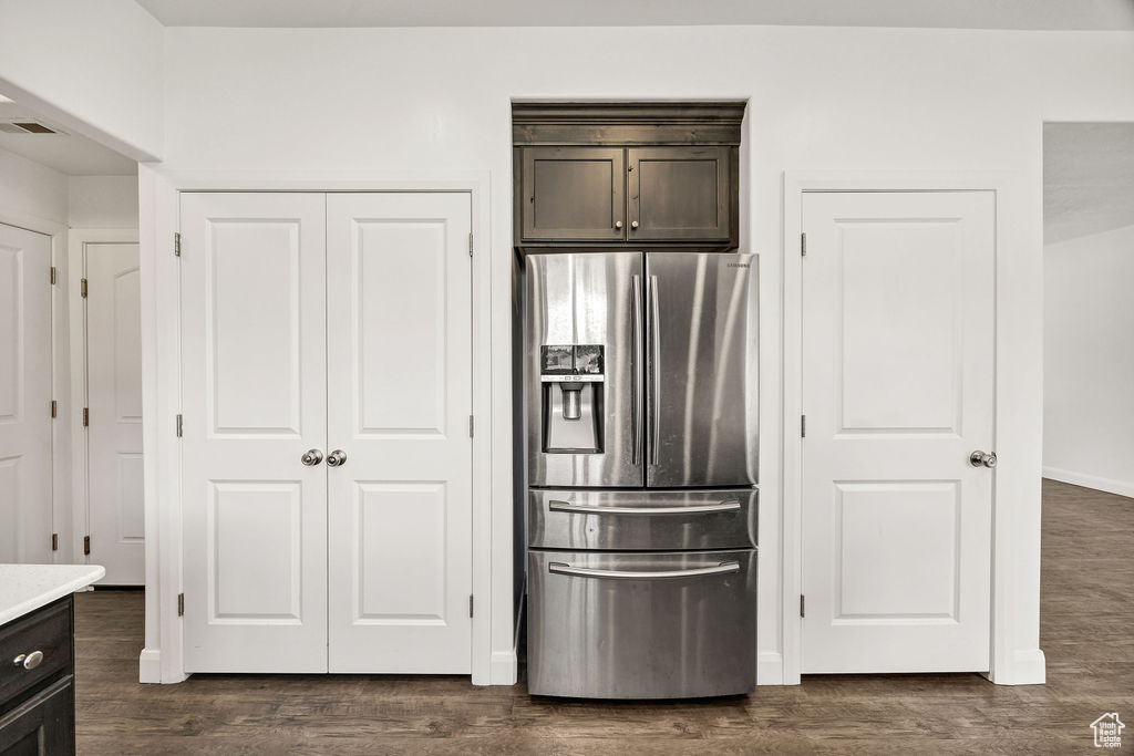 Kitchen with stainless steel fridge, dark brown cabinetry, dark wood-style flooring, light countertops, and baseboards
