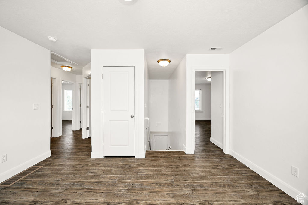Spare room with dark wood-type flooring, baseboards, and a smoke detector
