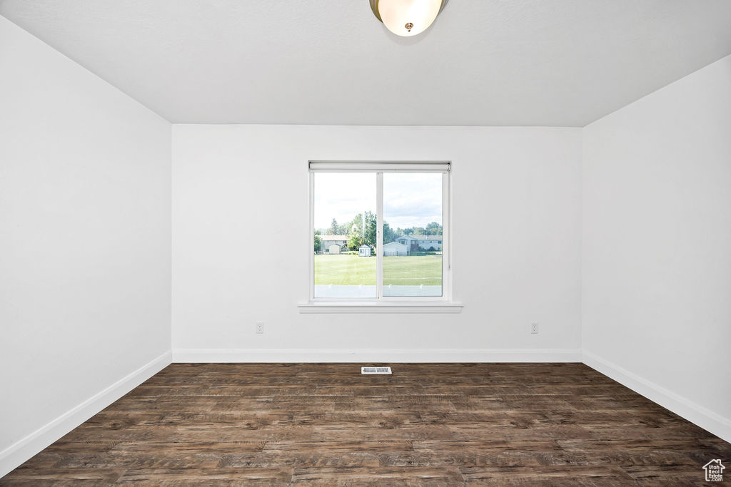 Unfurnished room featuring baseboards and dark wood-style flooring