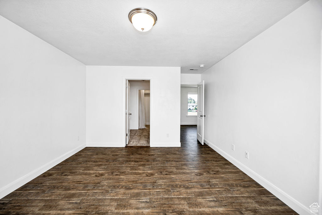 Spare room with baseboards and dark wood-style floors