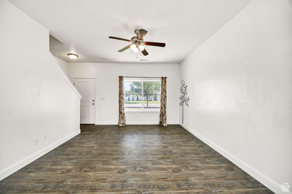 Spare room featuring a ceiling fan, baseboards, and dark wood-style flooring