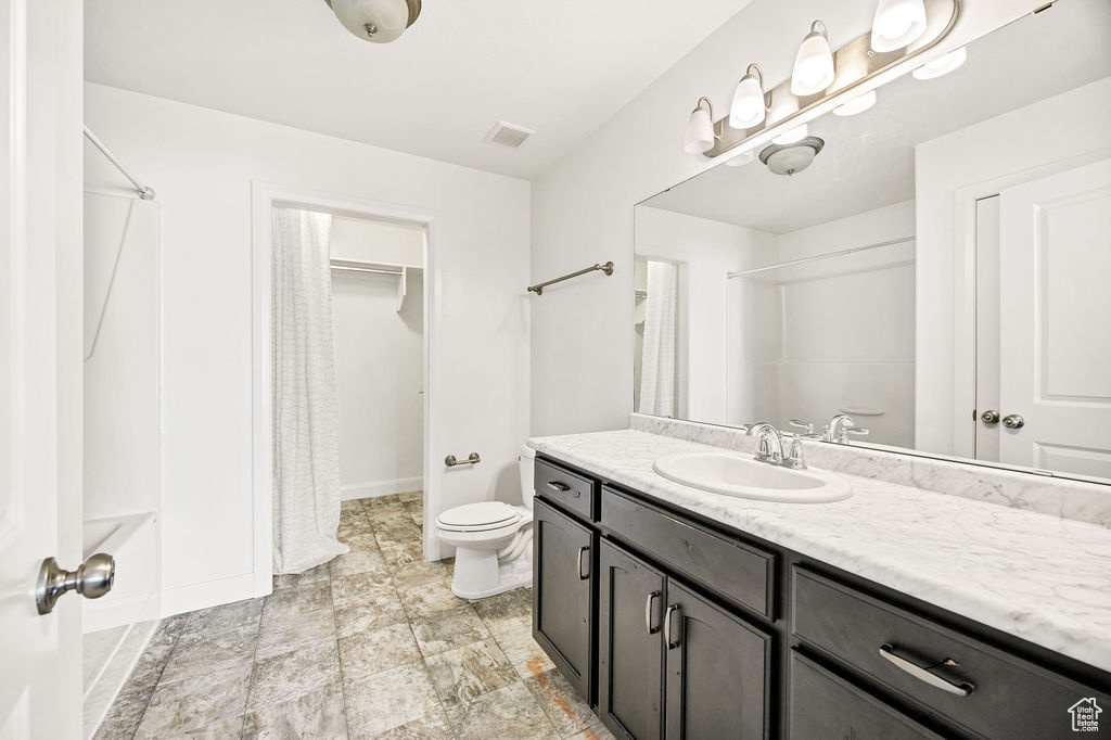 Bathroom featuring vanity, a shower with curtain, toilet, and baseboards