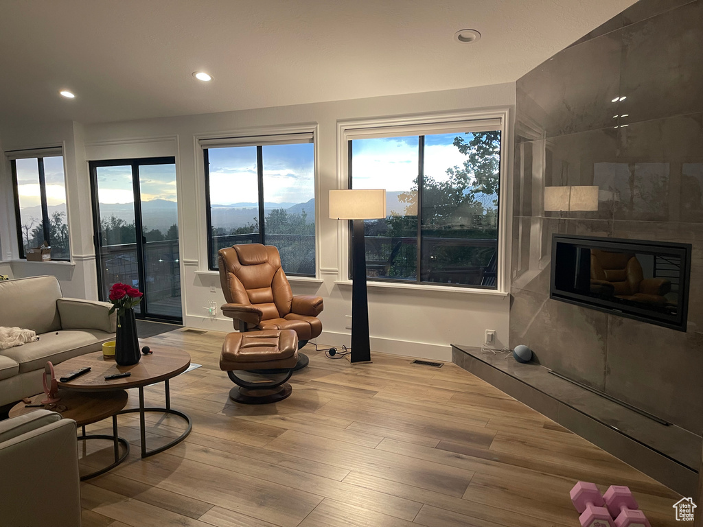 Living room featuring wood finished floors, plenty of natural light, recessed lighting, and a tiled fireplace