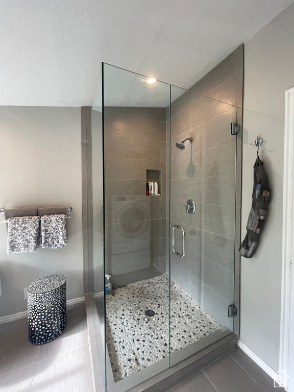 Bathroom with tile patterned floors, baseboards, and a stall shower