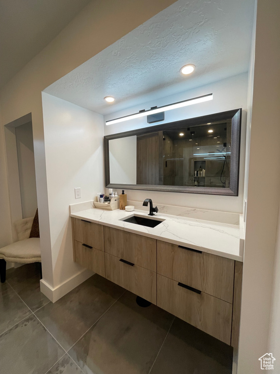 Bathroom featuring double vanity, a stall shower, baseboards, recessed lighting, and tile patterned floors