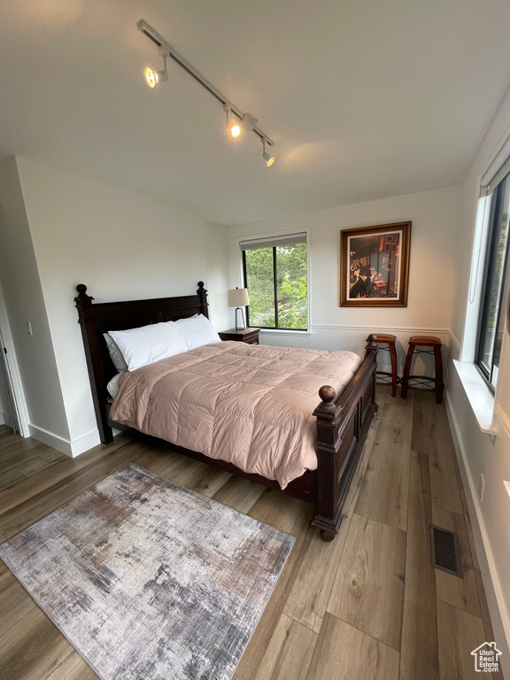 Bedroom featuring track lighting, wood finished floors, and baseboards