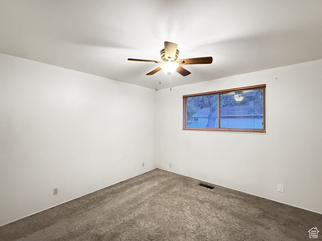 Carpeted spare room with a ceiling fan