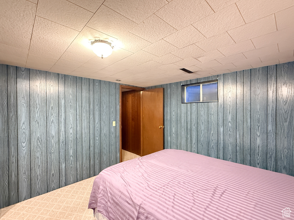 Bedroom featuring wood walls and carpet