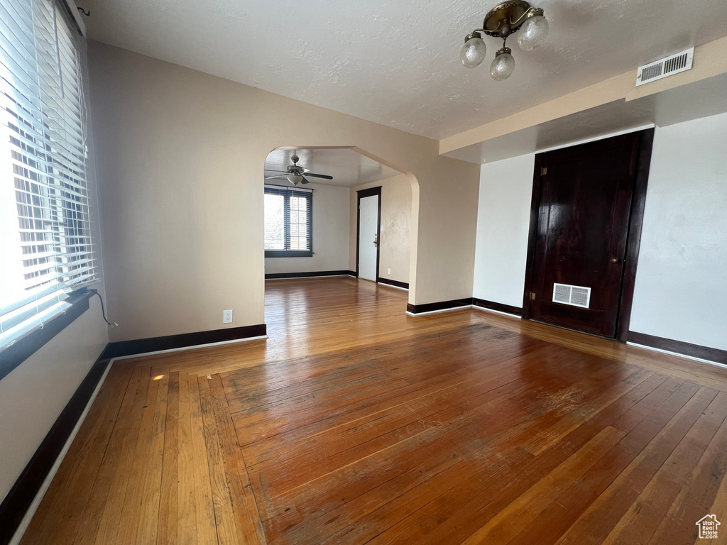 Spare room featuring arched walkways, wood-type flooring, a ceiling fan, and baseboards