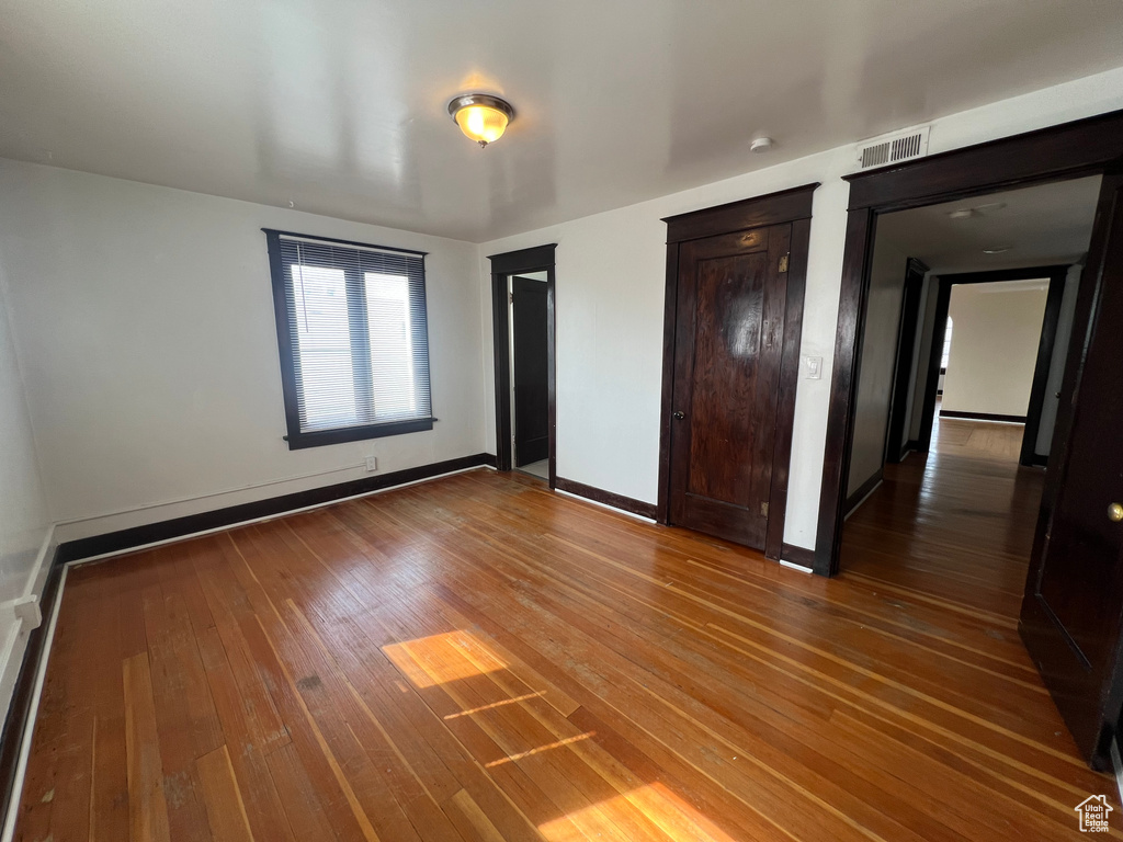 Unfurnished bedroom with wood-type flooring, two closets, and baseboards