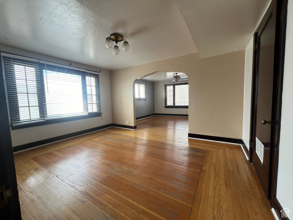 Empty room featuring arched walkways, wood-type flooring, and baseboards