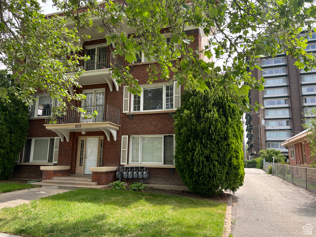 View of front of home featuring a balcony and brick siding