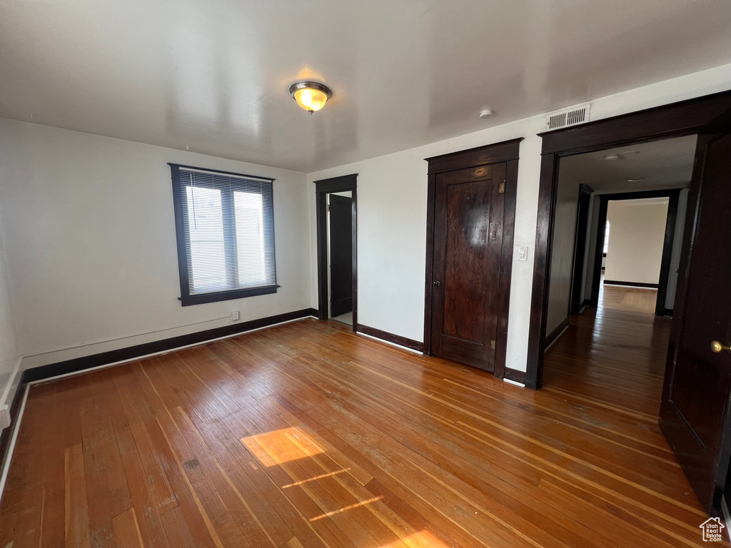 Unfurnished bedroom featuring hardwood / wood-style floors, multiple closets, and baseboards