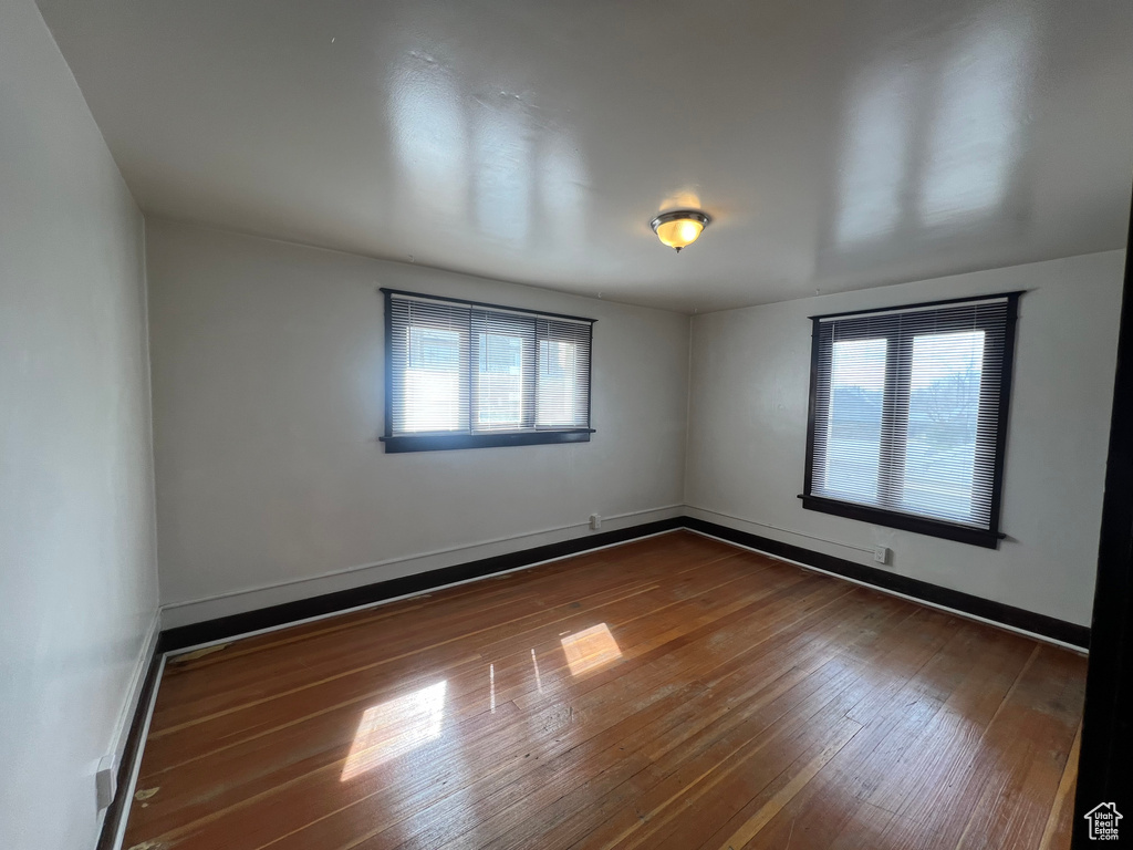 Unfurnished room with hardwood / wood-style floors, healthy amount of natural light, and baseboards