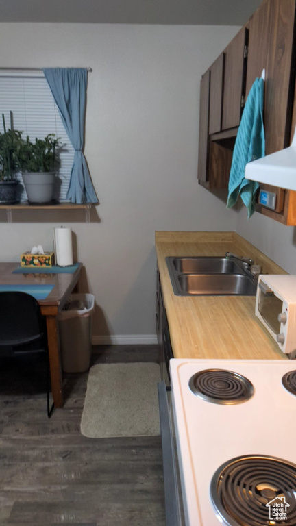 Kitchen featuring electric range, a sink, baseboards, dark wood finished floors, and an office area