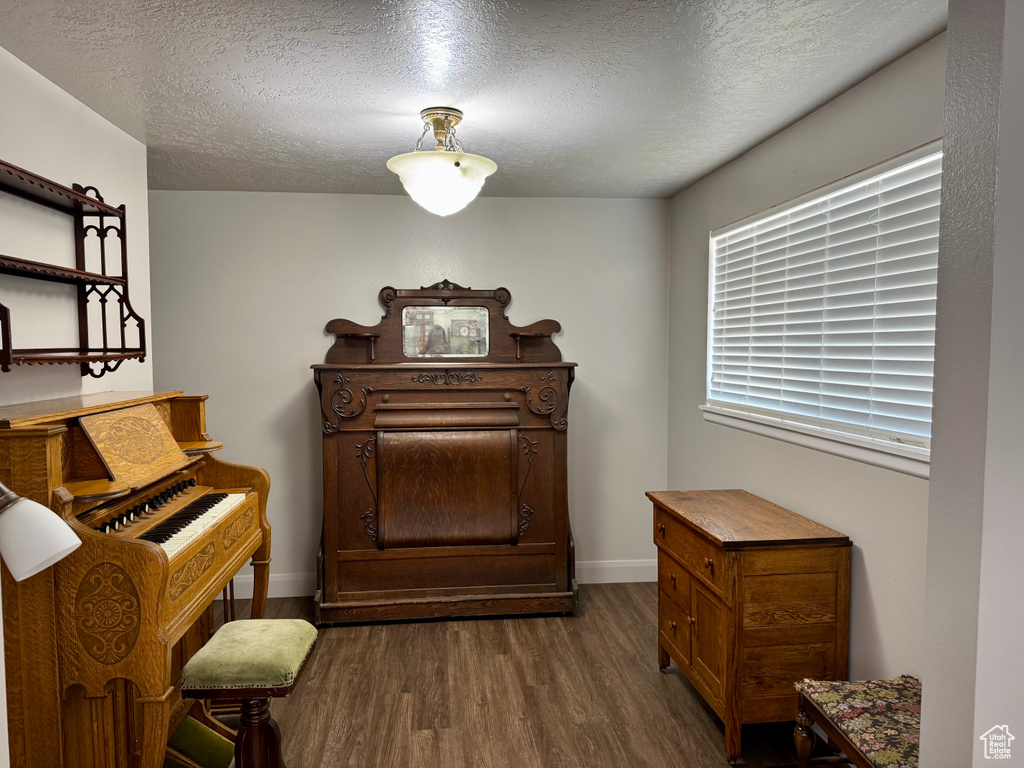 Living area featuring dark wood finished floors, a textured ceiling, and baseboards