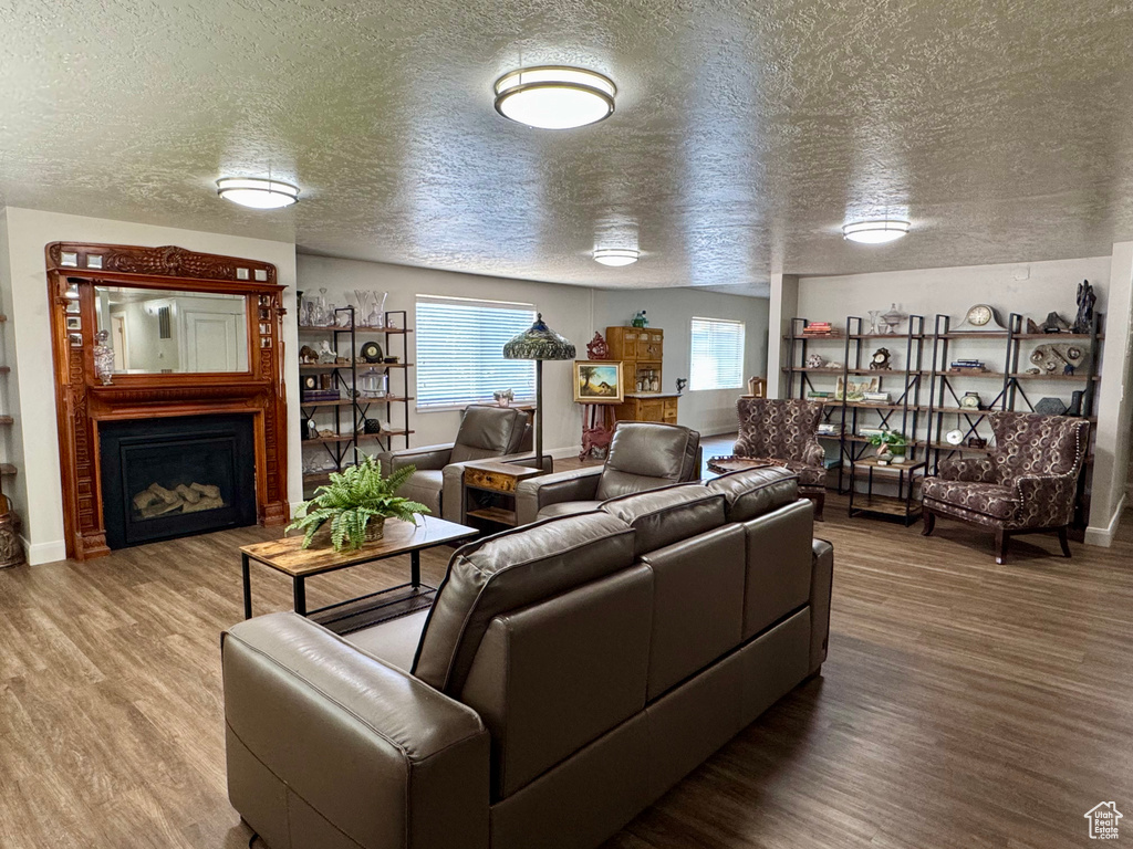 Living room with a textured ceiling, wood finished floors, and a fireplace