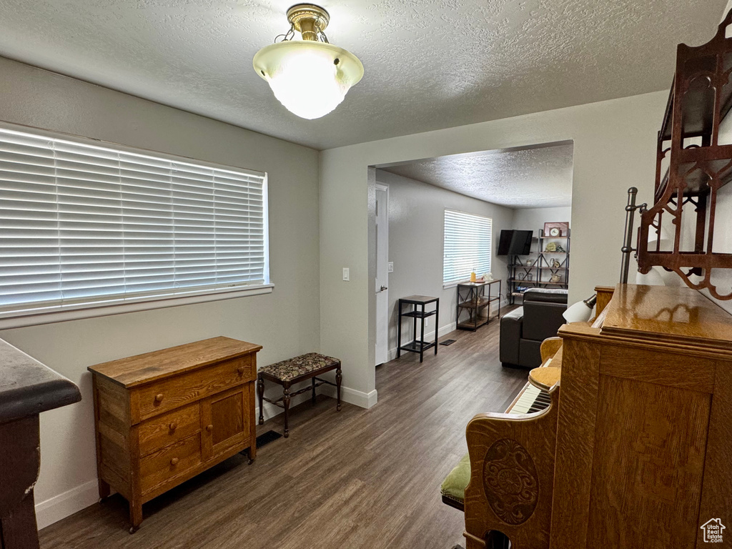 Living area featuring a textured ceiling, wood finished floors, and baseboards