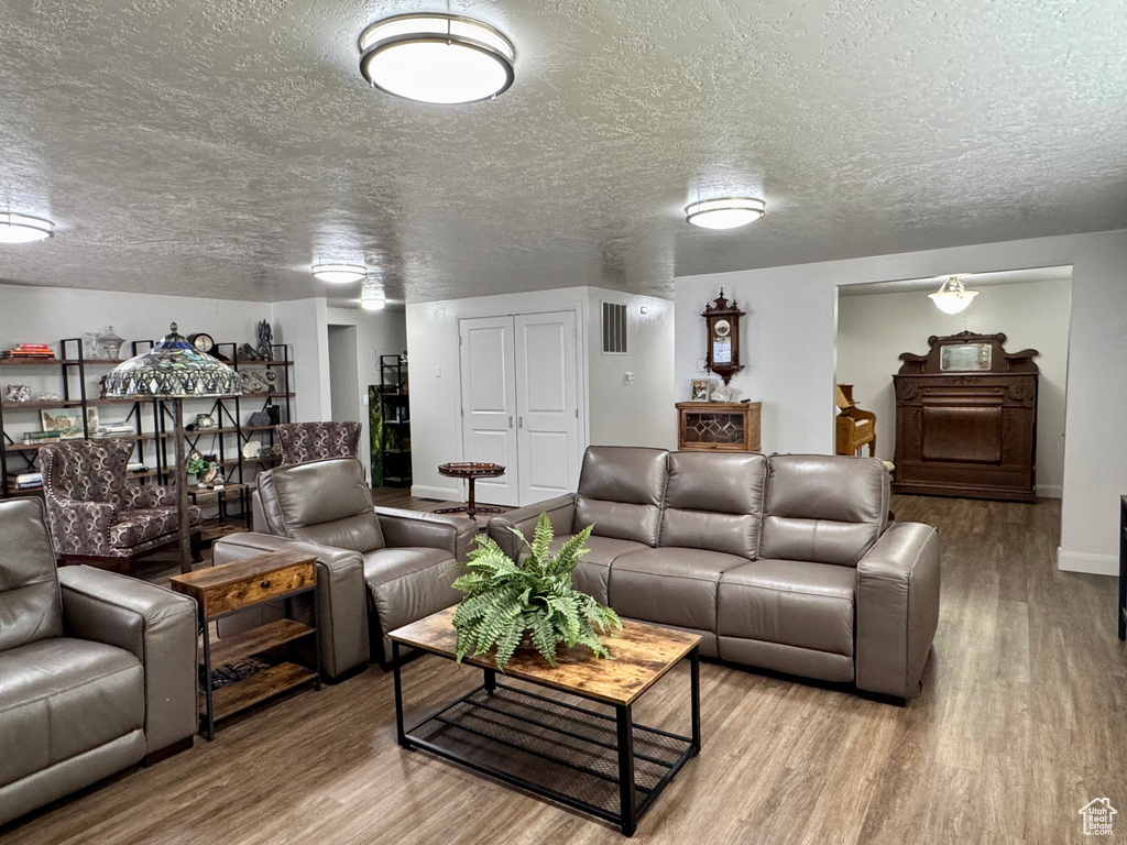 Living room featuring wood finished floors, a textured ceiling, and baseboards