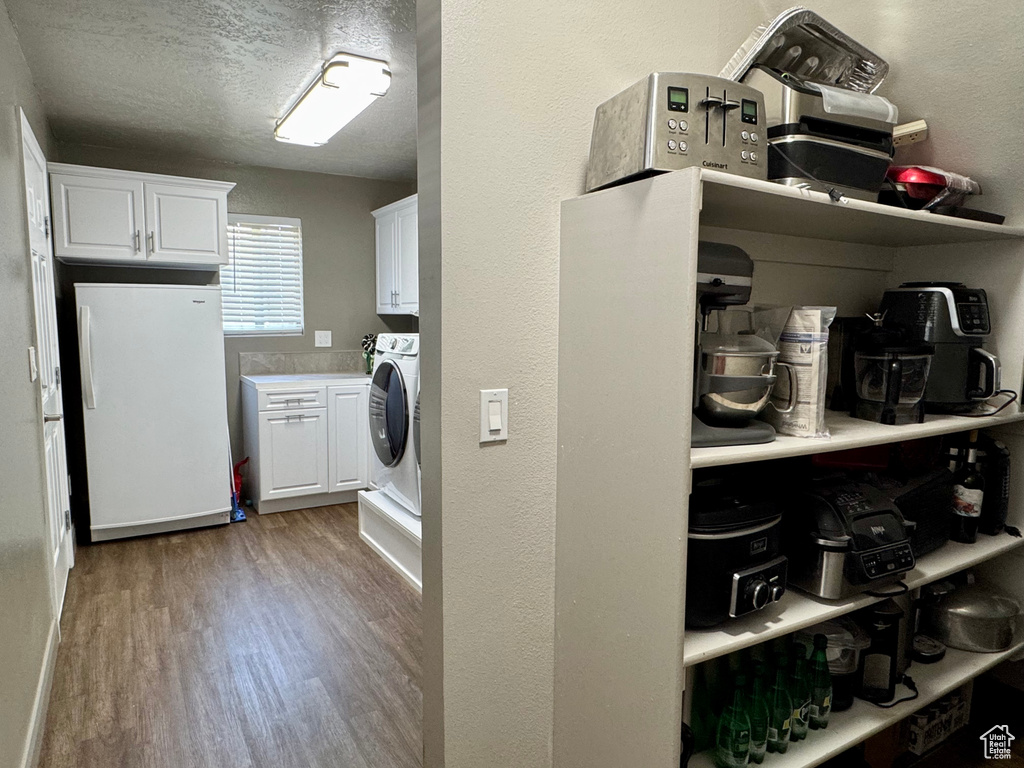 Washroom featuring washer / clothes dryer, light wood-style flooring, and a textured ceiling