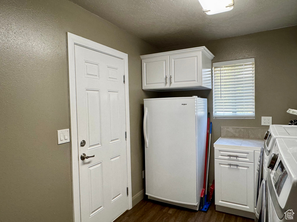 Laundry room with cabinet space, dark wood-style flooring, washer and dryer, a textured ceiling, and a textured wall