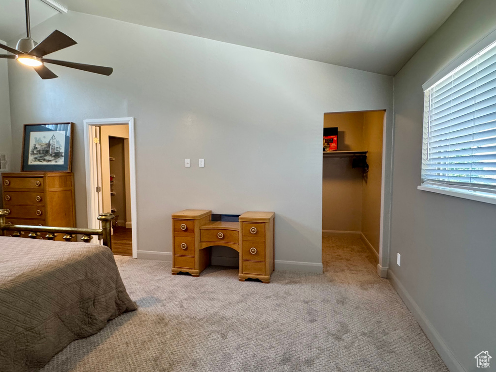 Bedroom with vaulted ceiling, a walk in closet, light colored carpet, baseboards, and a closet
