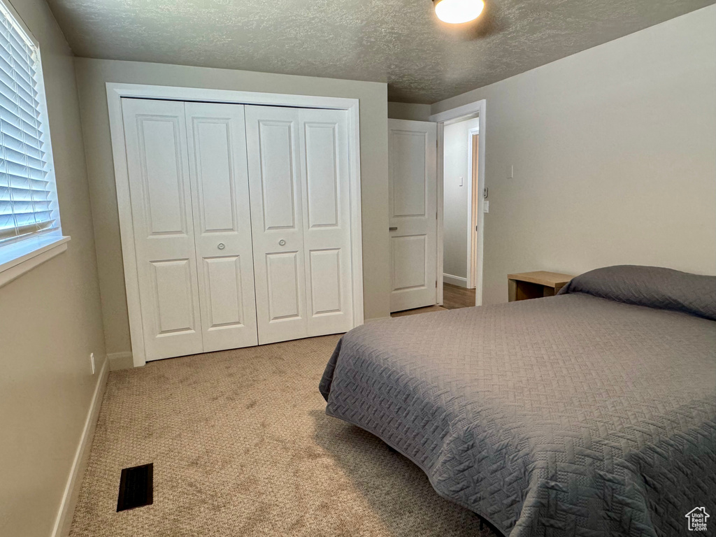Carpeted bedroom featuring a closet, baseboards, and a textured ceiling
