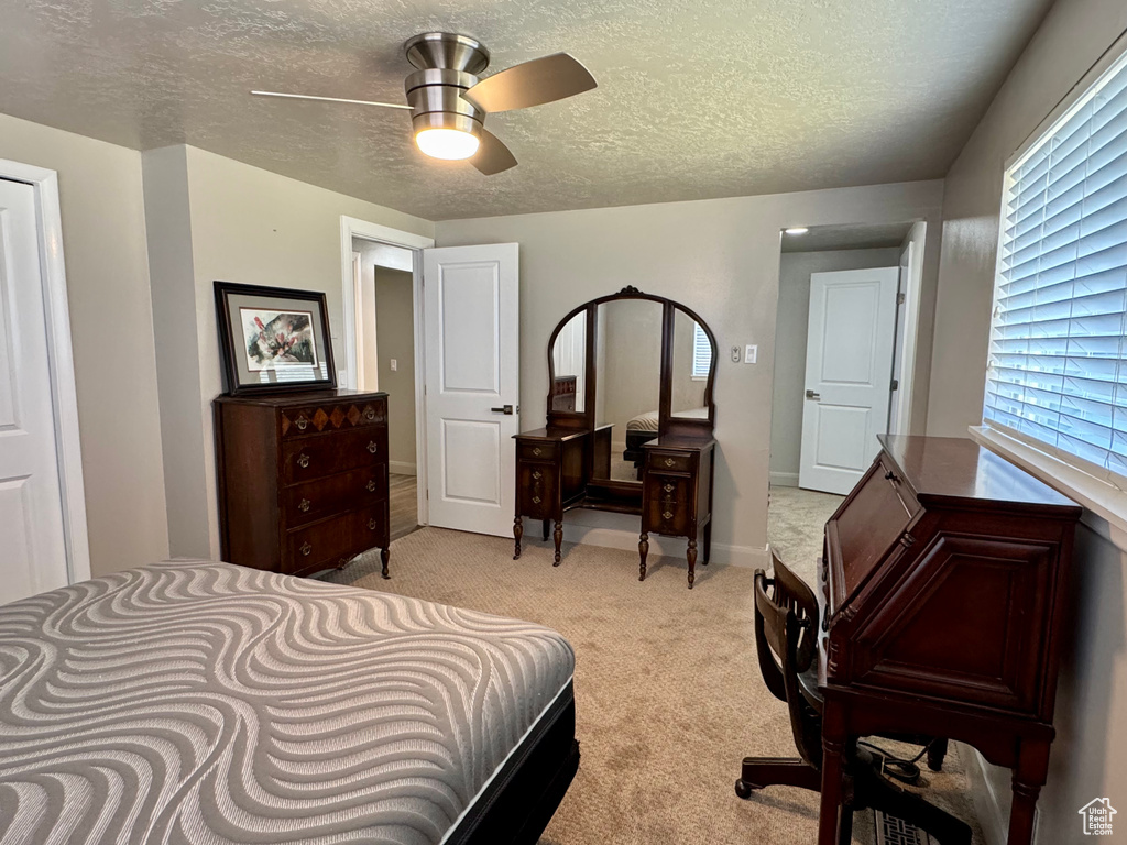 Bedroom featuring light carpet, a textured ceiling, and a ceiling fan