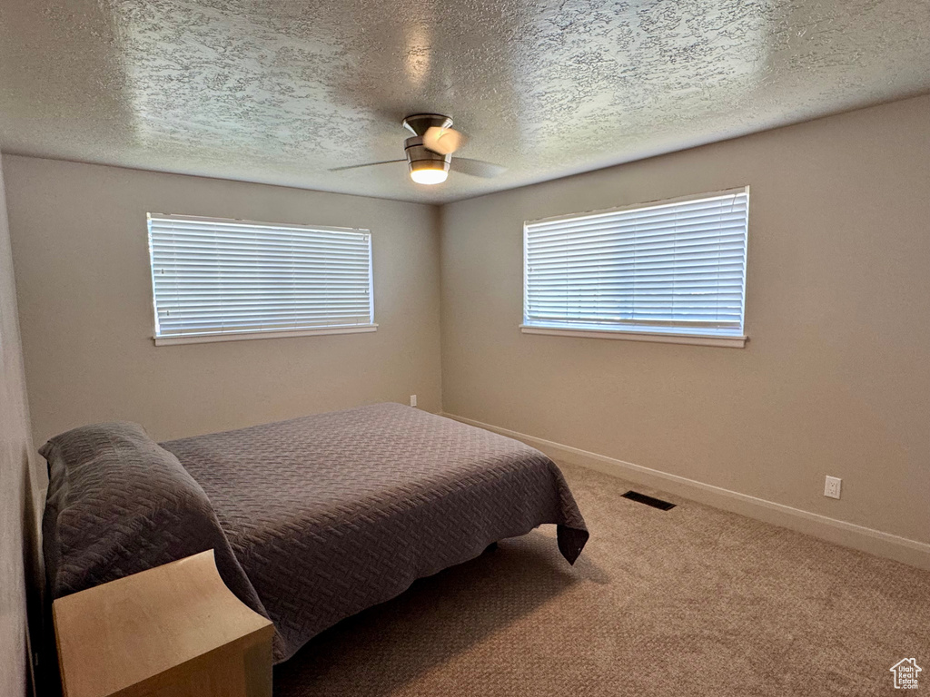 Bedroom featuring carpet floors, baseboards, a ceiling fan, and a textured ceiling