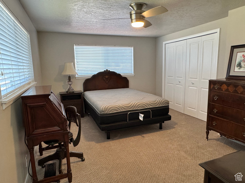 Bedroom with a closet, carpet, a ceiling fan, and a textured ceiling