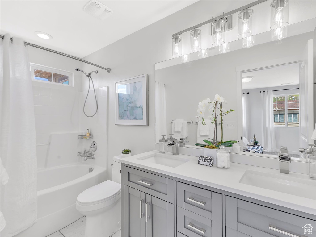 Full bath with shower / bath combo, double vanity, toilet, and tile patterned floors