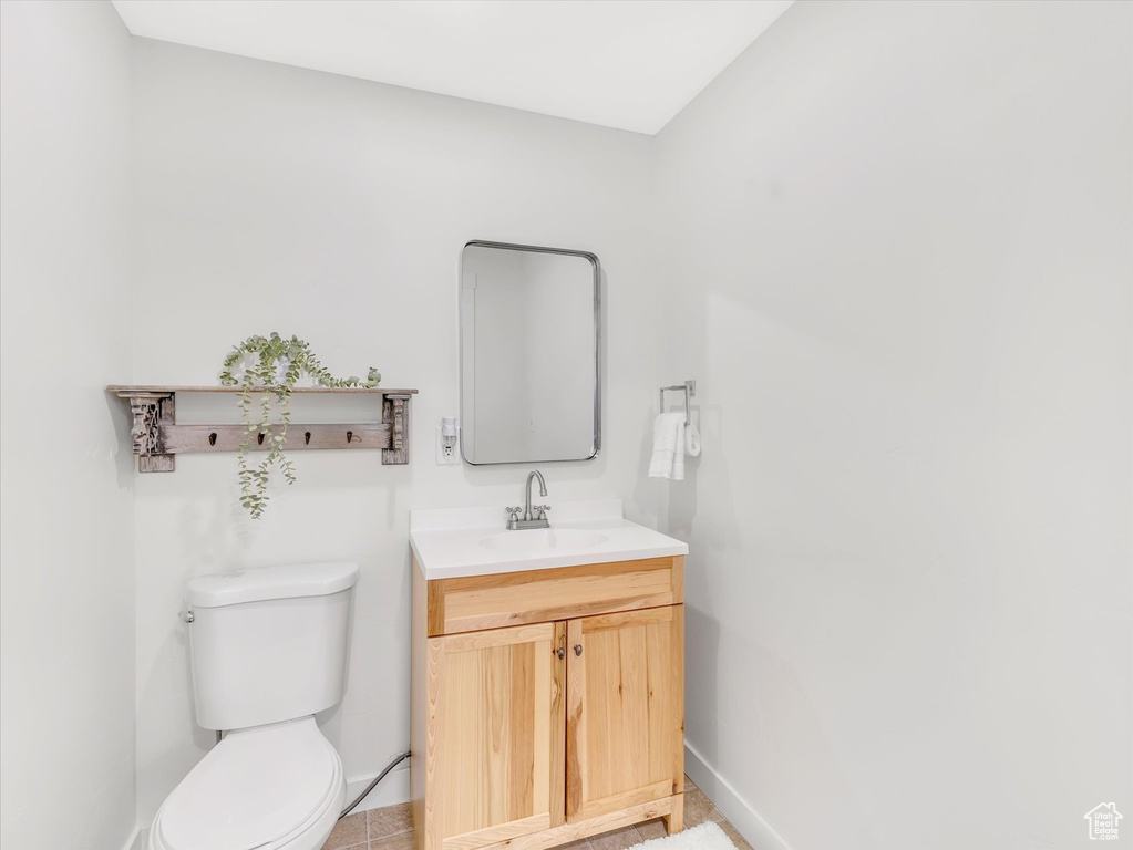 Half bathroom with vanity, toilet, and baseboards