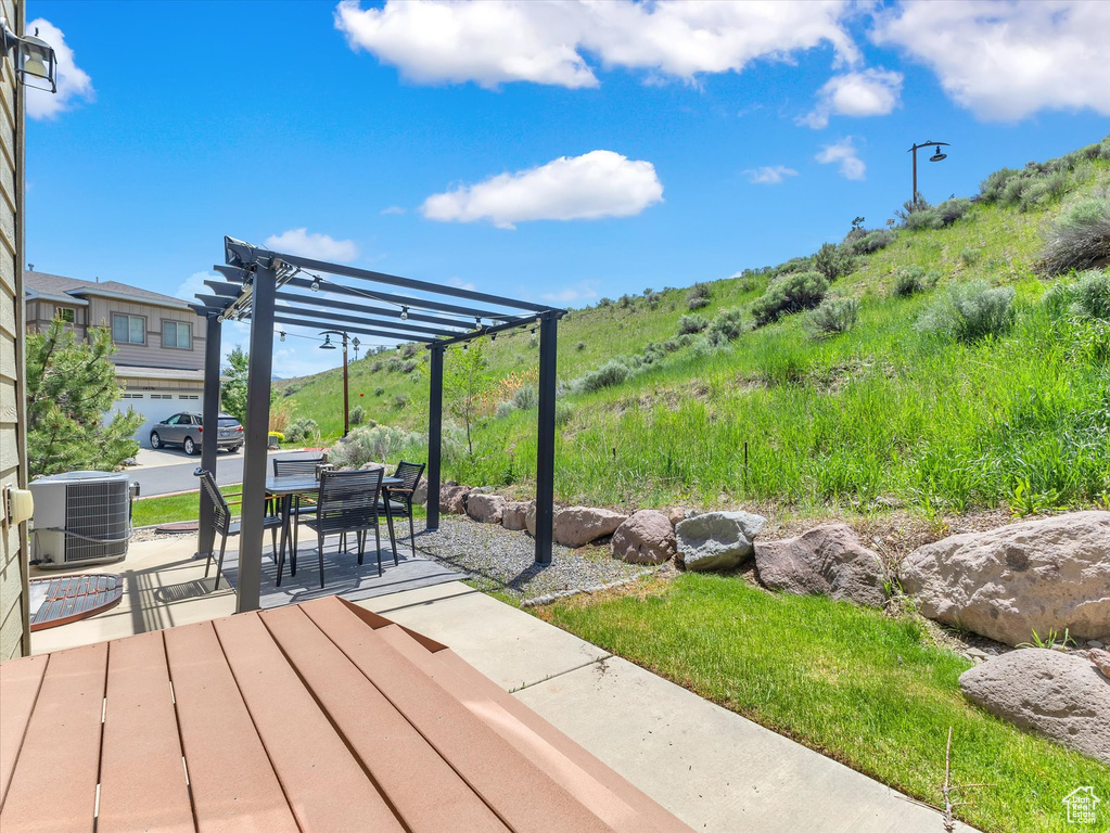 Wooden terrace with central air condition unit, a pergola, and a patio