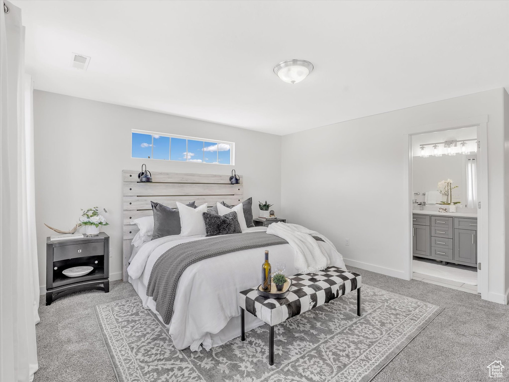 Bedroom featuring light colored carpet, ensuite bath, and baseboards