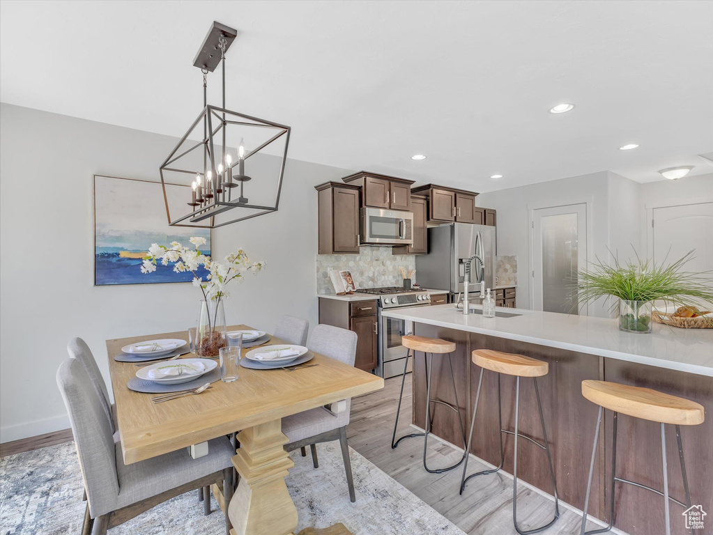Dining space featuring light wood-type flooring, a chandelier, and recessed lighting