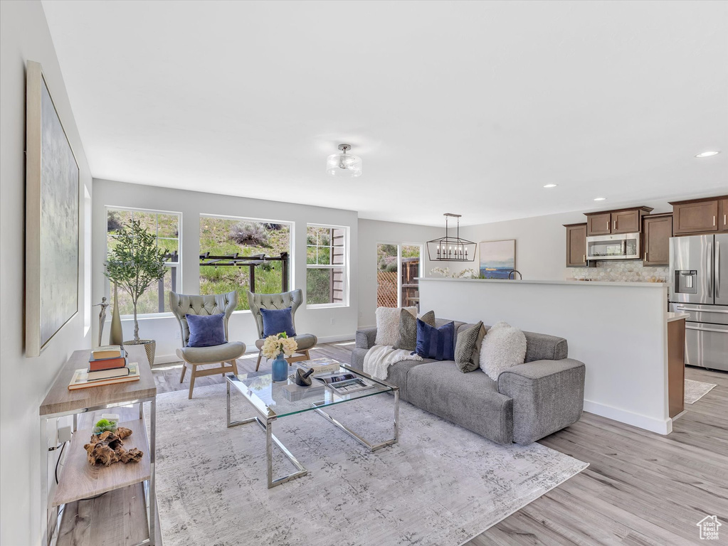 Living room featuring light wood-type flooring, recessed lighting, baseboards, and a chandelier