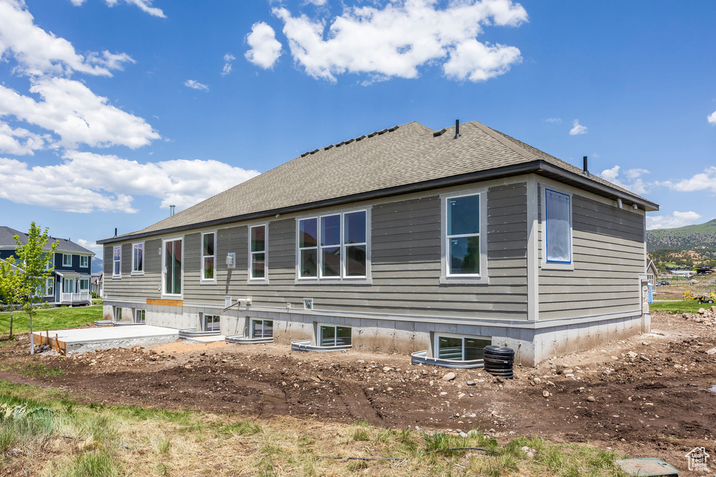 Rear view of property featuring a patio and a shingled roof