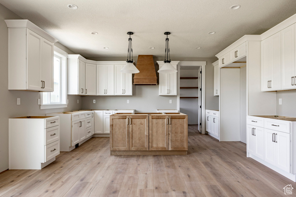Kitchen featuring premium range hood, a center island, light wood-style flooring, recessed lighting, and pendant lighting
