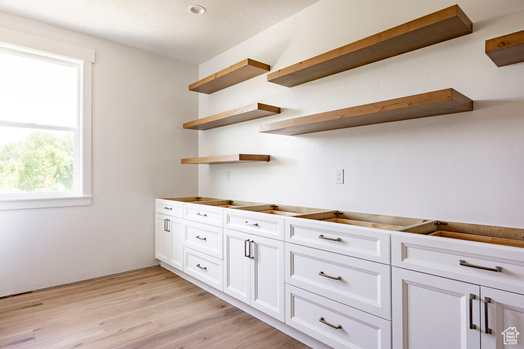 Kitchen featuring open shelves, white cabinetry, and light wood-style floors