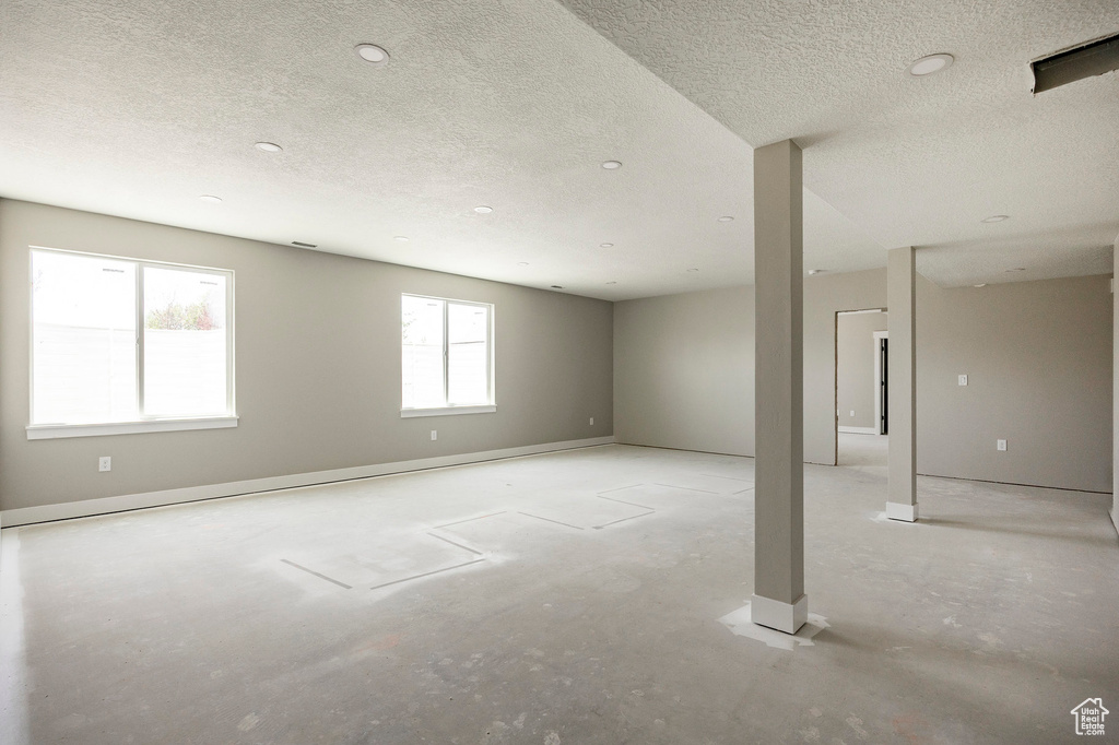Unfurnished room with a textured ceiling and concrete flooring