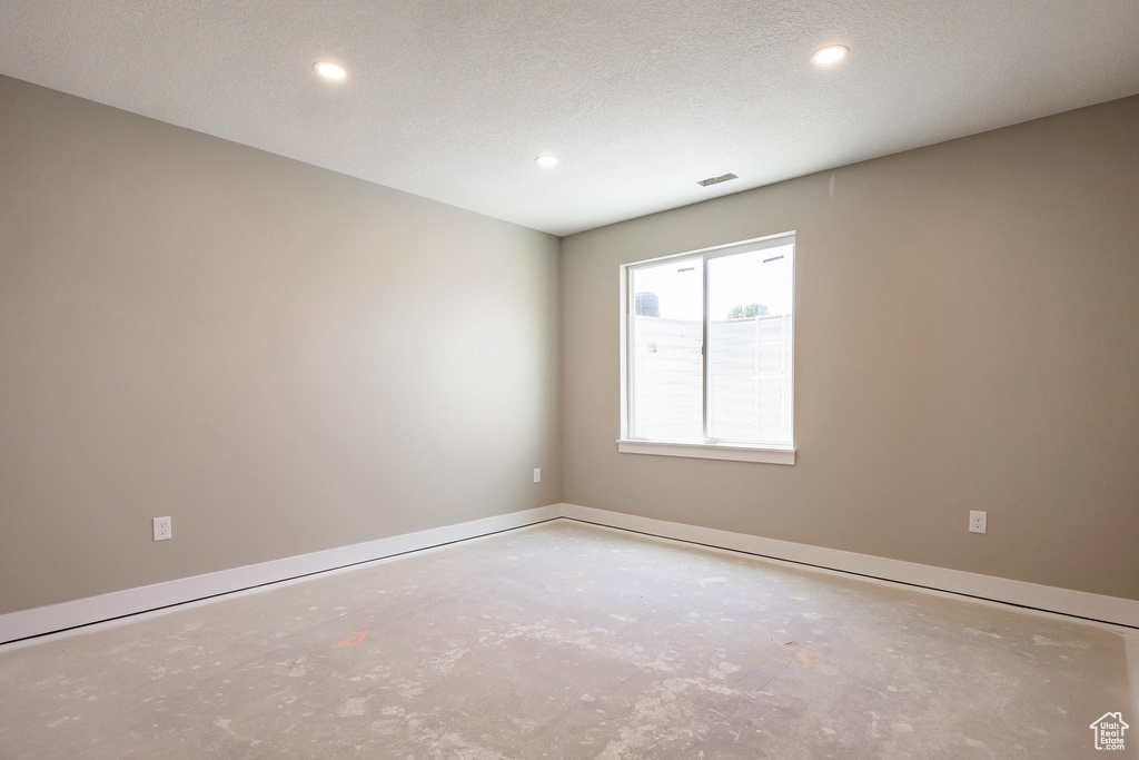 Empty room with unfinished concrete flooring and recessed lighting
