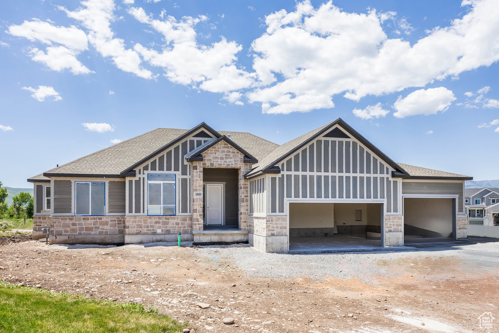 Craftsman-style house with stone siding, an attached garage, roof with shingles, and driveway