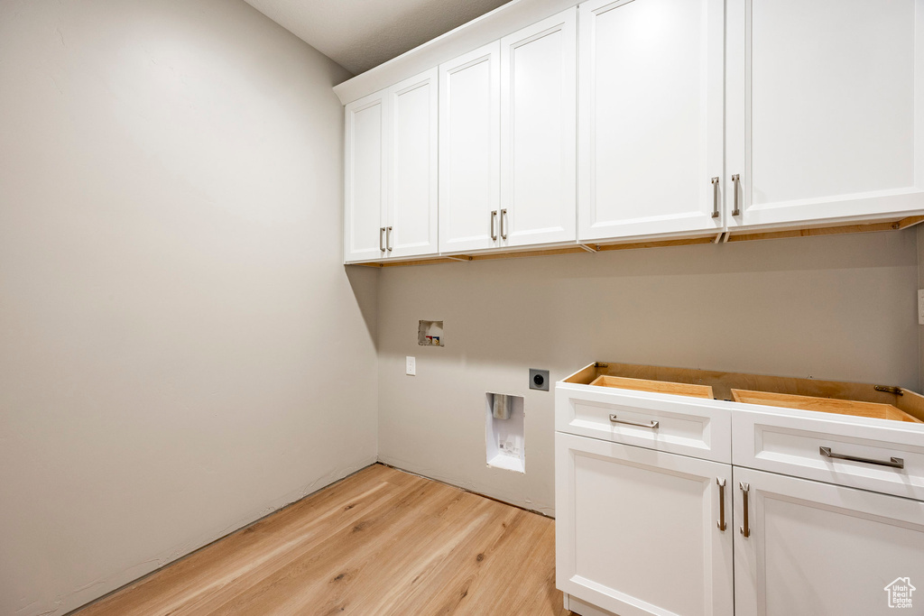 Washroom featuring hookup for an electric dryer, light wood-type flooring, hookup for a washing machine, and cabinet space