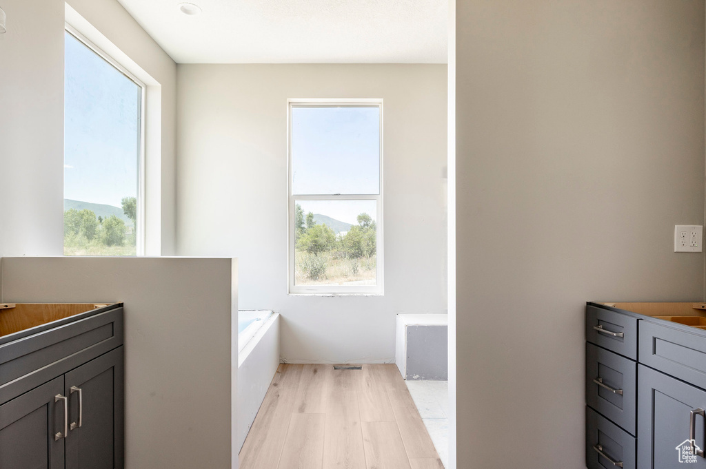 Bathroom featuring a bath, healthy amount of natural light, and wood finished floors