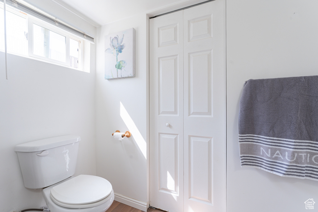 Bathroom with toilet, a closet, and wood finished floors