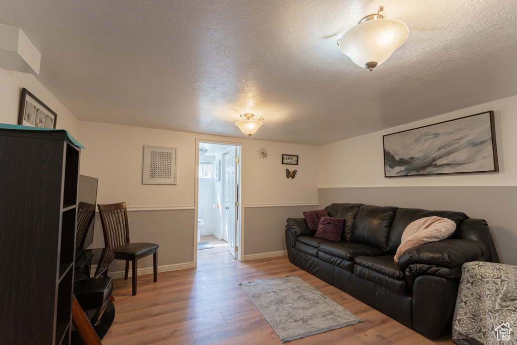 Living room with wood finished floors, a textured ceiling, and baseboards