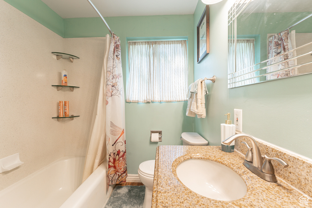 Full bath featuring shower / bath combo with shower curtain, toilet, and vanity