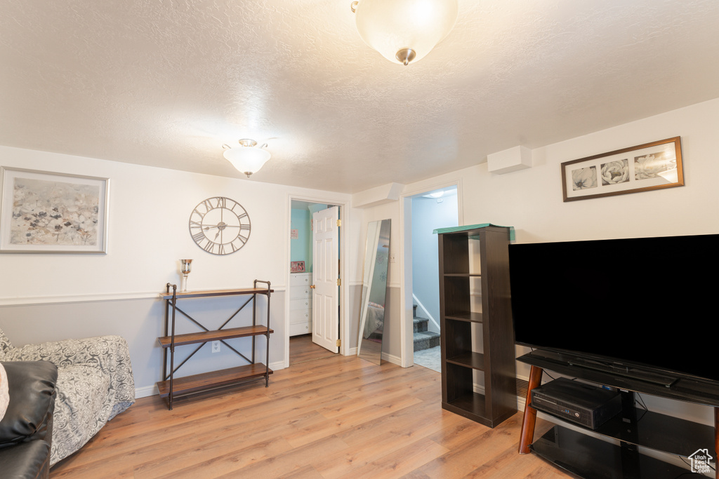 Living area with light wood-type flooring, baseboards, and a textured ceiling