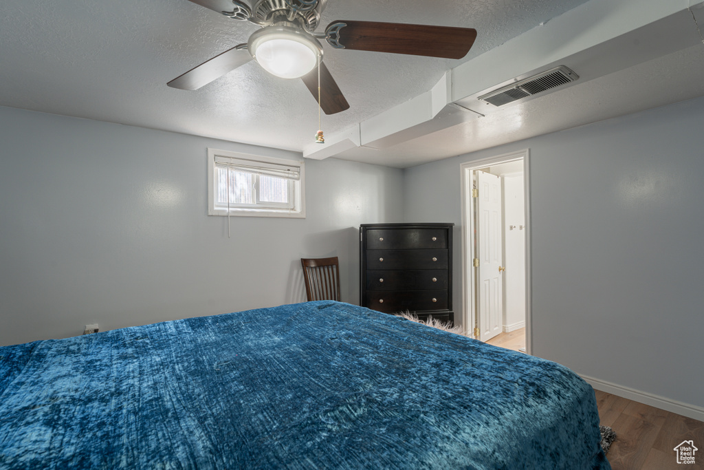 Bedroom featuring wood finished floors, a textured ceiling, baseboards, and ceiling fan